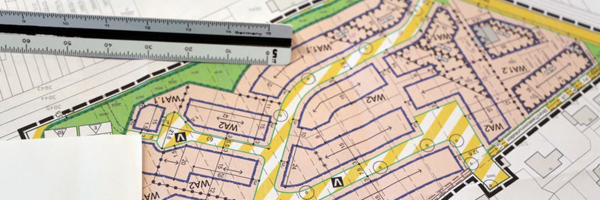 Zeichnung von einem Baugebiet mit Straßenführung, Lineal und Schriftstück