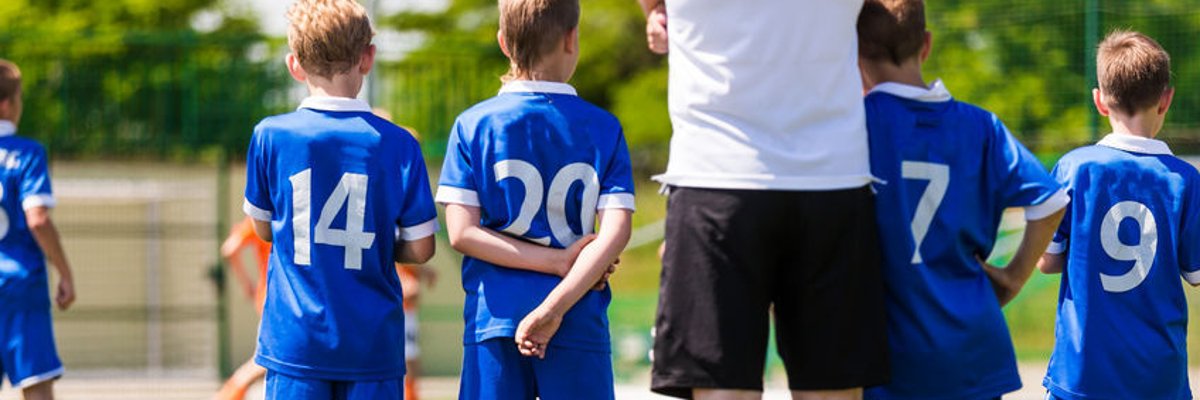Trainer vier jungen Spielern die auf ihren Einsatz warten