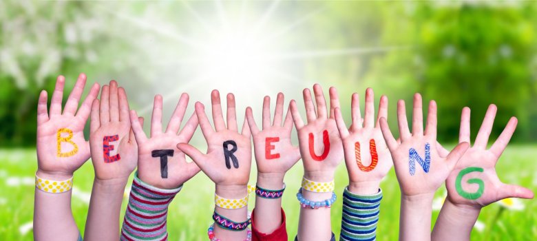 Kids Hands Holding Word Betreuung Means Day Care, Grass Meadow Kids Hands Holding Word Betreuung Means Day Care, Grass Meadow