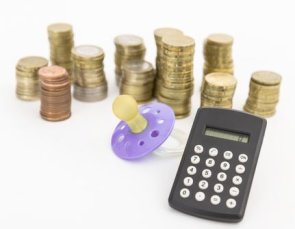 Schnuller mit hartem Geld und kleinem Taschenrechner auf hellem Hintergrund