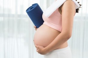 Aktive und sportliche Schwangerschaft Abgeschnittenes Bild einer sportlichen Schwangeren mit Yogamatte