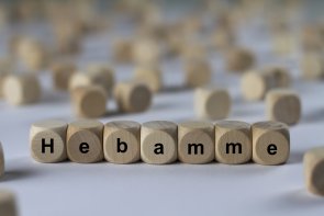 verschwommener Hintergrund, Holzwürfel mit der Aufschrift Hebamme