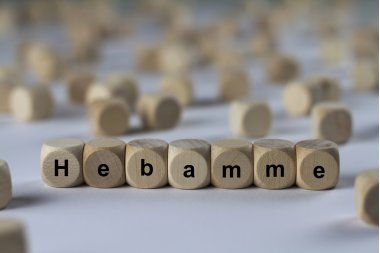 Hebamme - Holzwürfel mit Buchstaben verschwommener Hintergrund, Holzwürfel mit der Aufschrift Hebamme