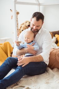 Glücklicher Vater hält kleinen Baby-Sohn. Vater spielt mit Baby im Kinderzimmer