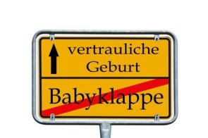 gelbes Ortsschild mit den Aufschriften vertrauliche Geburt und mit rot durchgestrichene Babyklappe