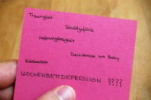 rosa Zettel mit Begriffen in einer Hand