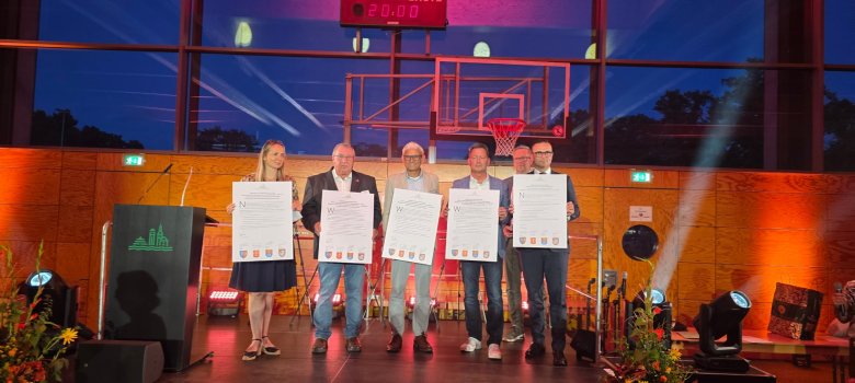 5 Personen stehen auf einer Bühne in einer Sporthalle und halten je eine Urkunde in ihren Händen