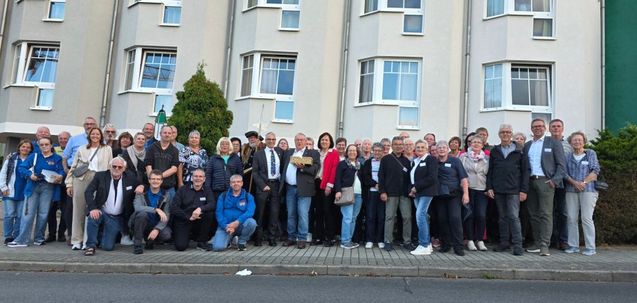 Eine große Gruppe steht vor einem Hotelgebäude und lächelt in die Kamera