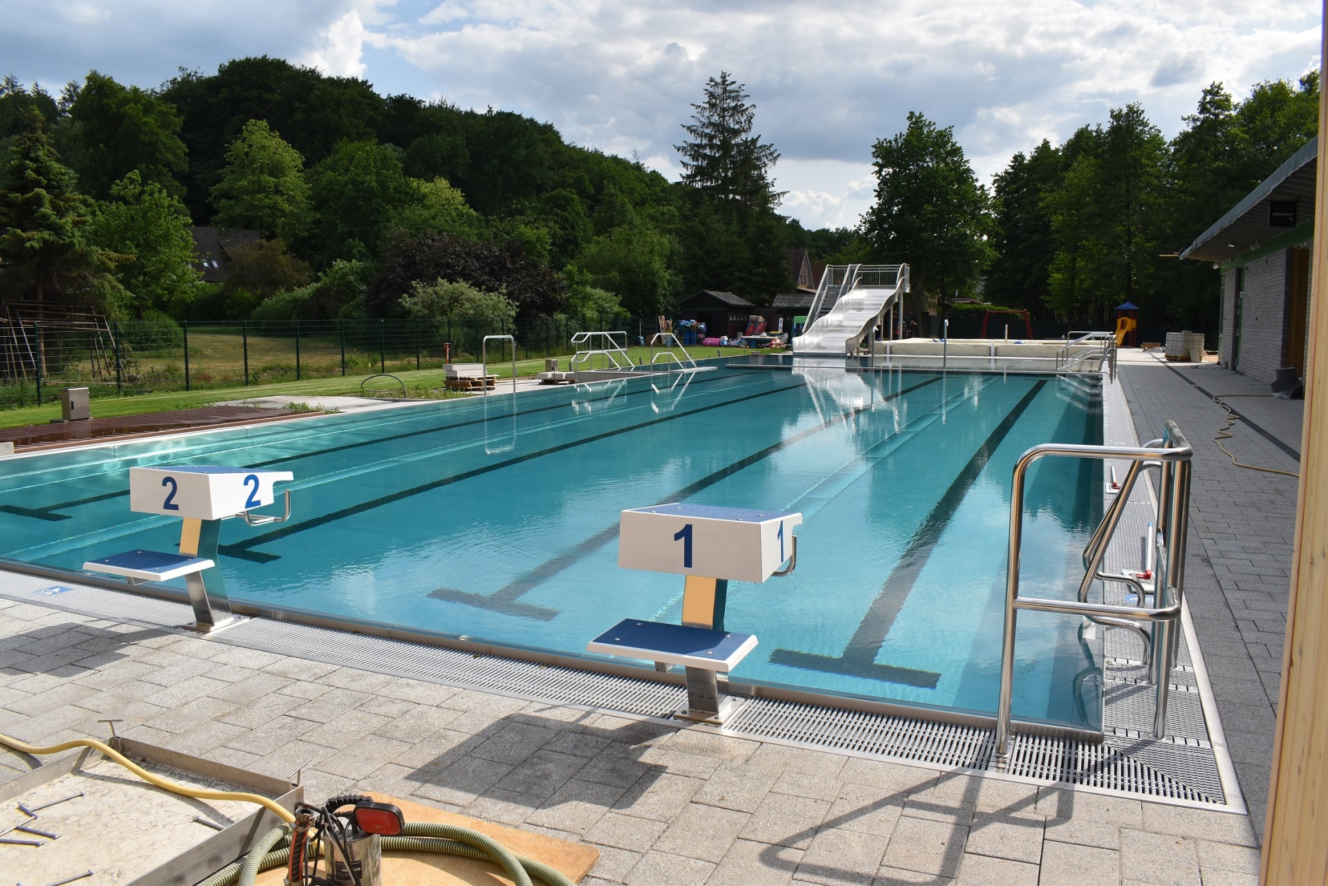 leeres Freibad mit zwei Startrampen einer Rutsche und Randabgrenzungen
