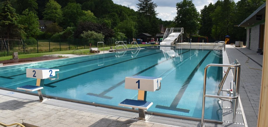leeres Freibad mit zwei Startrampen einer Rutsche und Randabgrenzungen