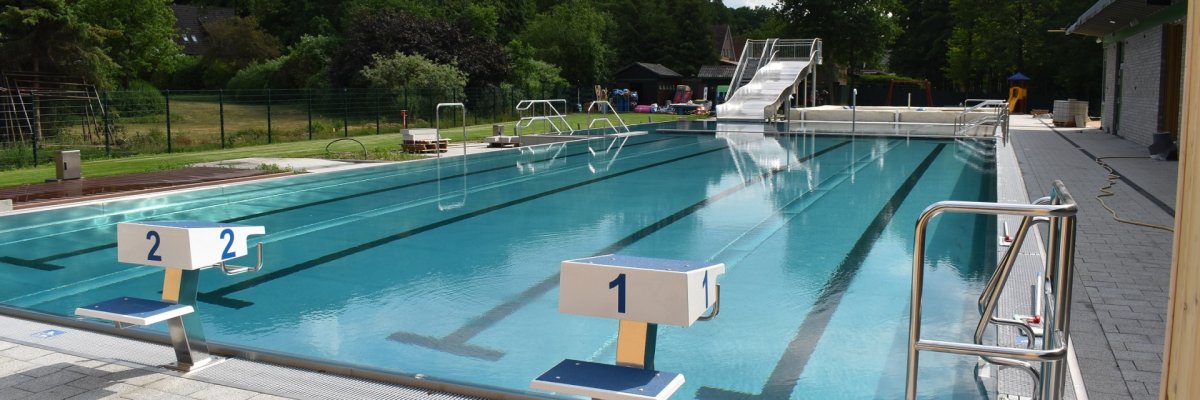 leeres Freibad mit zwei Startrampen einer Rutsche und Randabgrenzungen