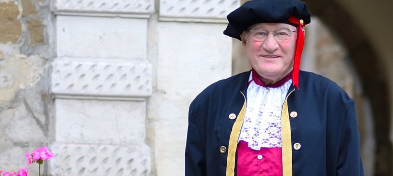 ein Mann in mittelalterlichen Kleidung steht vor einem Portal mit Blumentopf