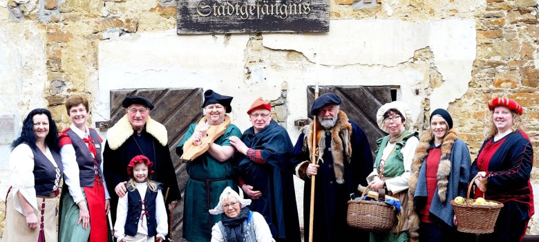 mehrere Personen mit mittelalterlicher Kleidung vor dem ehemaligen Stadtgefängnis der Stadt Fürstenau