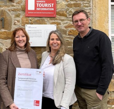 4 Personen-Team mit Urkunde vor Mauer